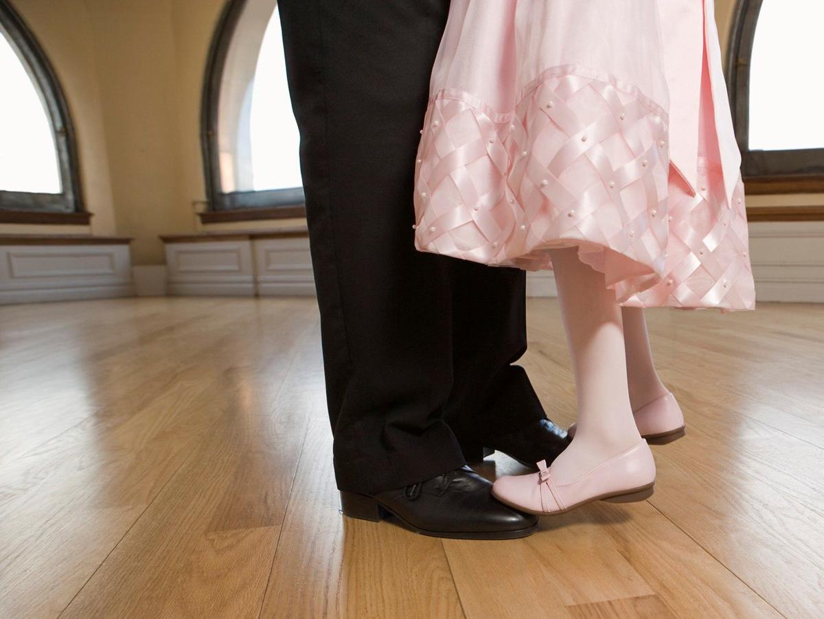 Daughter standing on feet of father dancing